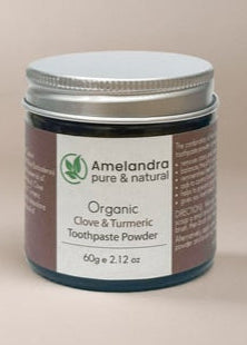 Amelandra organic clove and turmeric toothpaste powder jar on a beige background